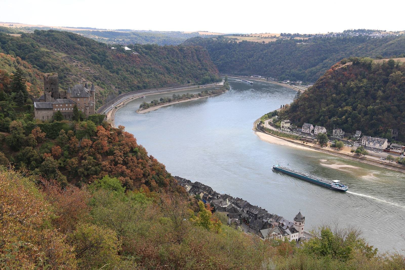 The Rhine curving past Sankt Goarshausen in autumn, with Burg Katz on the wooded slope and a ship on the river