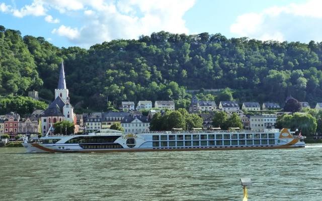 A Rhine passenger ship passing the riverside town of St. Goar below wooded hills