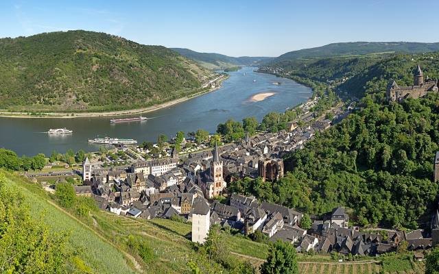 Bacharach and its church below wooded hills and vineyards, beside a wide bend of the Rhine