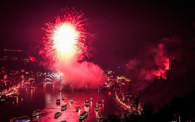 Red fireworks and flares lighting up the Rhine and a convoy of boats at night