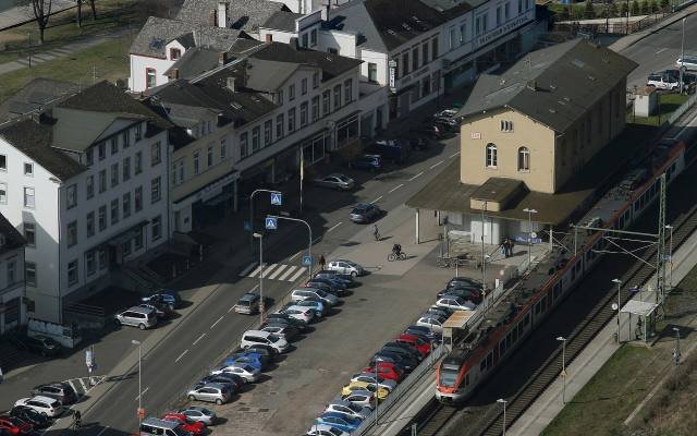 A red regional train running along the Rhine through Sankt Goarshausen, seen from the hillside above