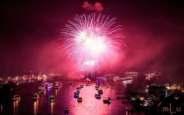 Pink fireworks bursting over a fleet of lit-up boats on the Rhine at St. Goarshausen