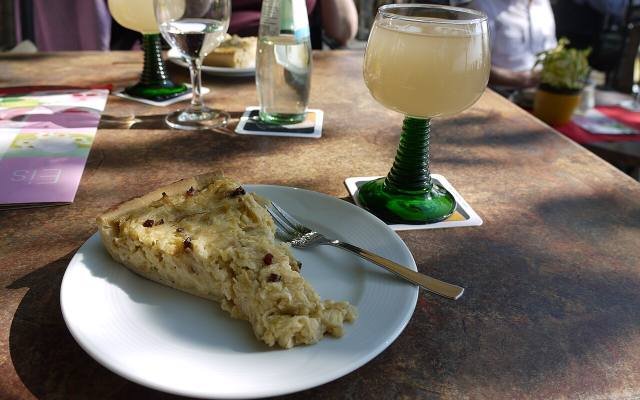 Glasses of new wine and a slice of onion tart on a café table